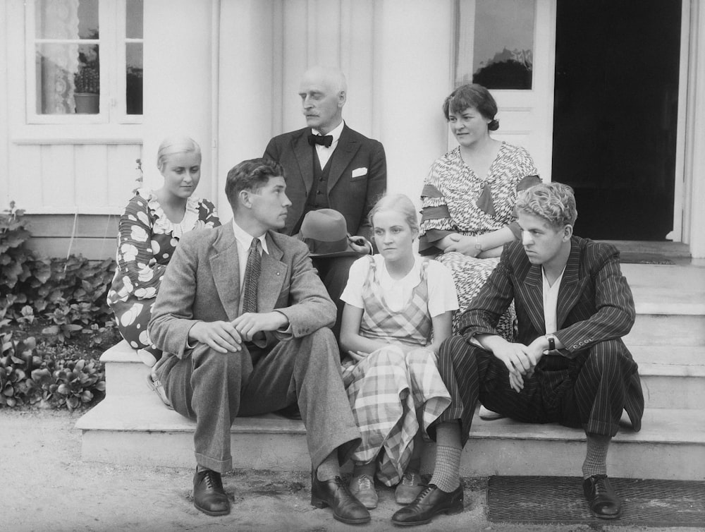 a group of people sitting on the steps of a house