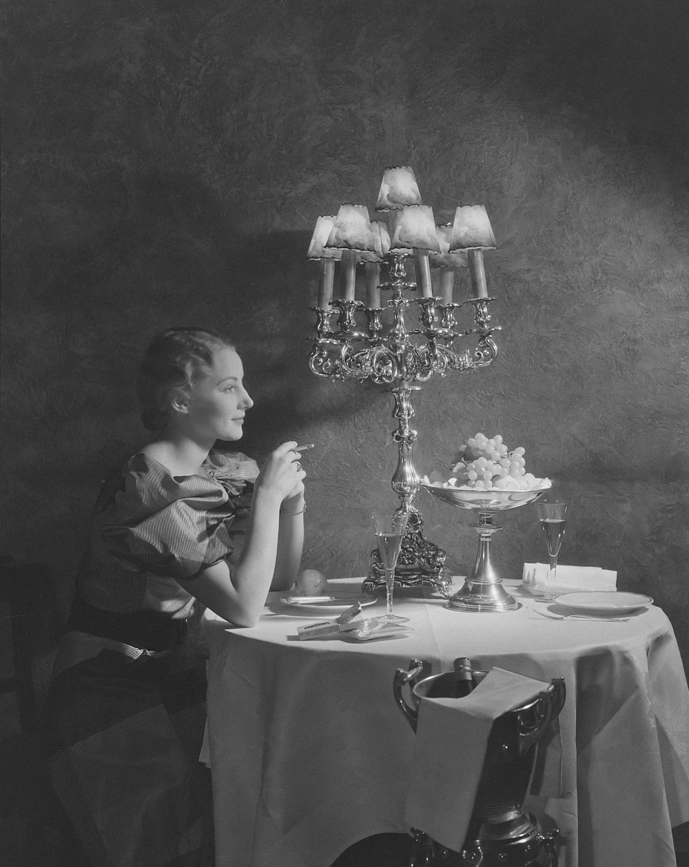 a black and white photo of a woman sitting at a table
