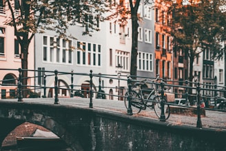 Bicycles parked along a canal with colorful houses reflecting in the water at sunset.
