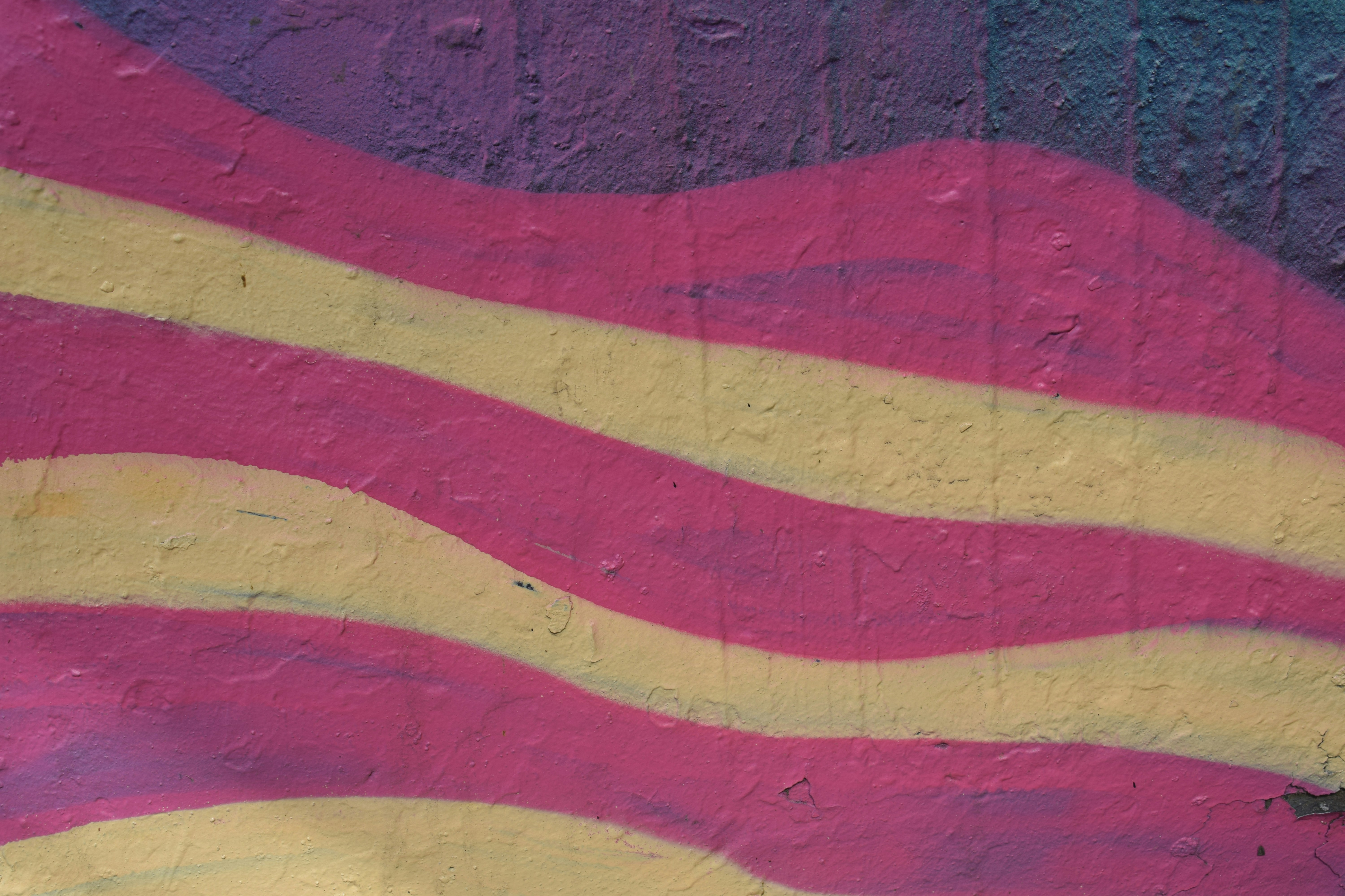 A painting of a pink and yellow wave on the side of a building photo ...