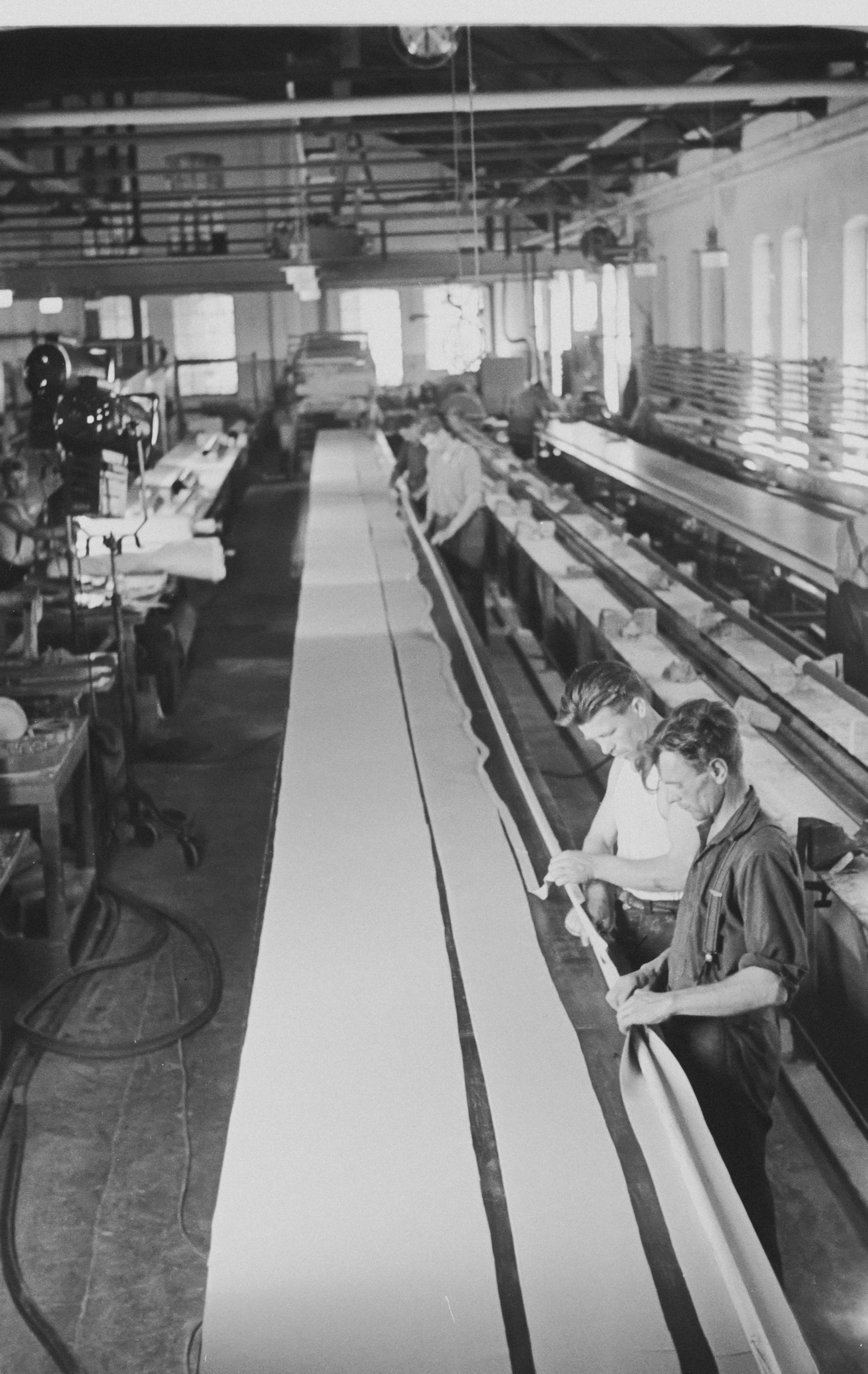 a black and white photo of people working in a factory