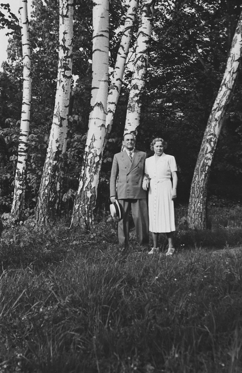 an old photo of a man and a woman standing in front of some trees