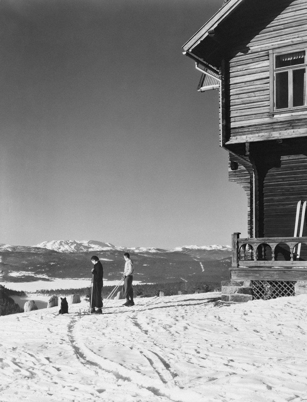 a black and white photo of two people standing in the snow