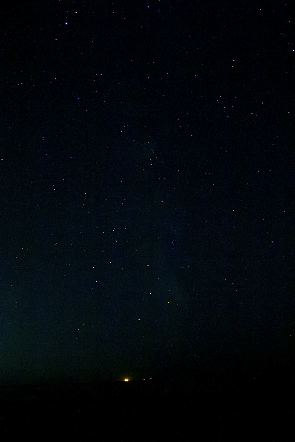 a night sky with stars and a plane in the distance