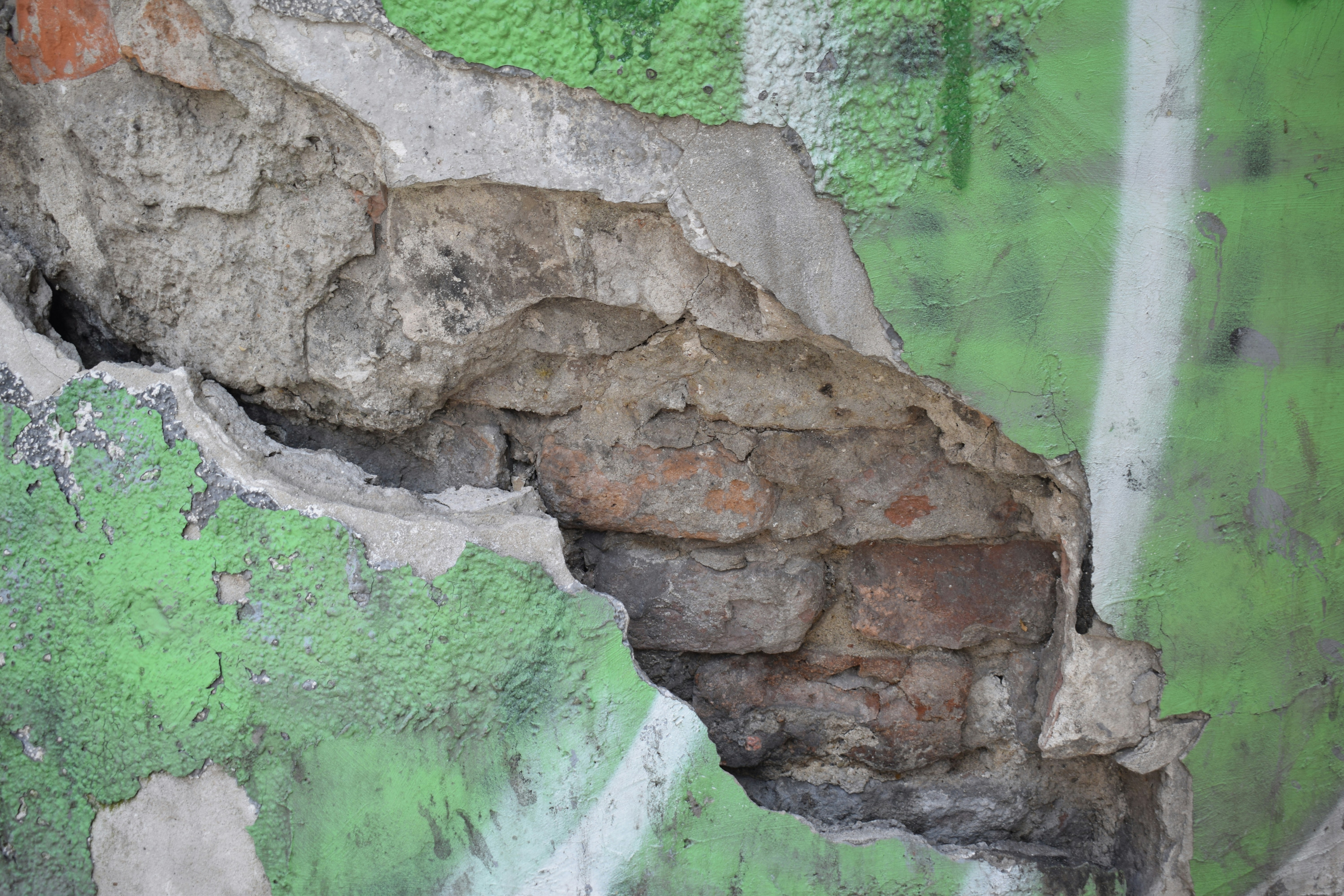 a green and white wall with a large crack in it