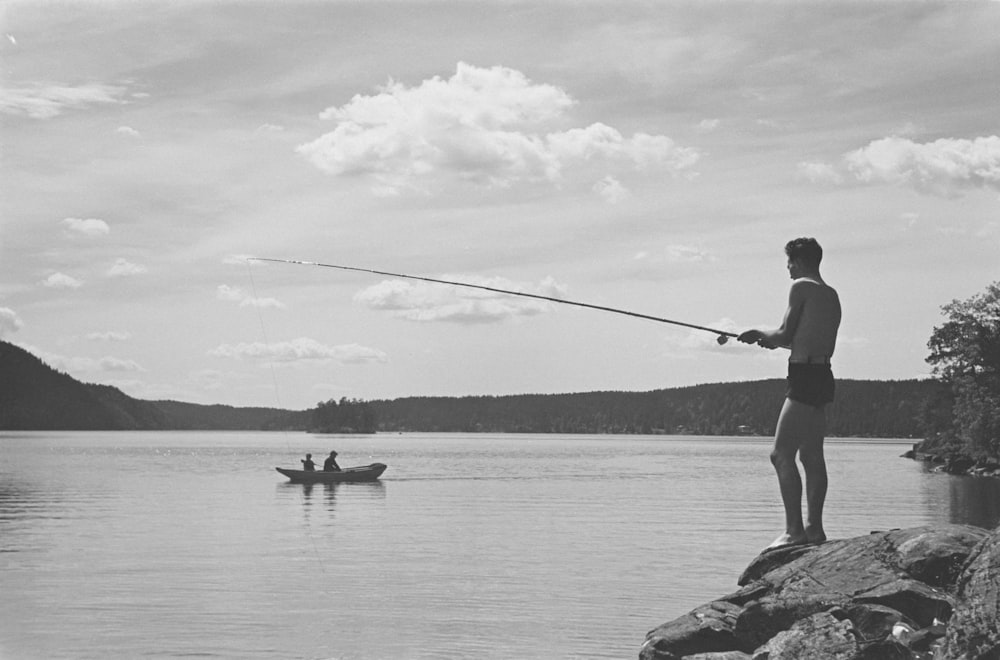 a man standing on a rock while holding a fishing rod