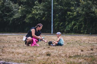 A volunteer gently handing a water bottle to a grateful child in a sunlit village.