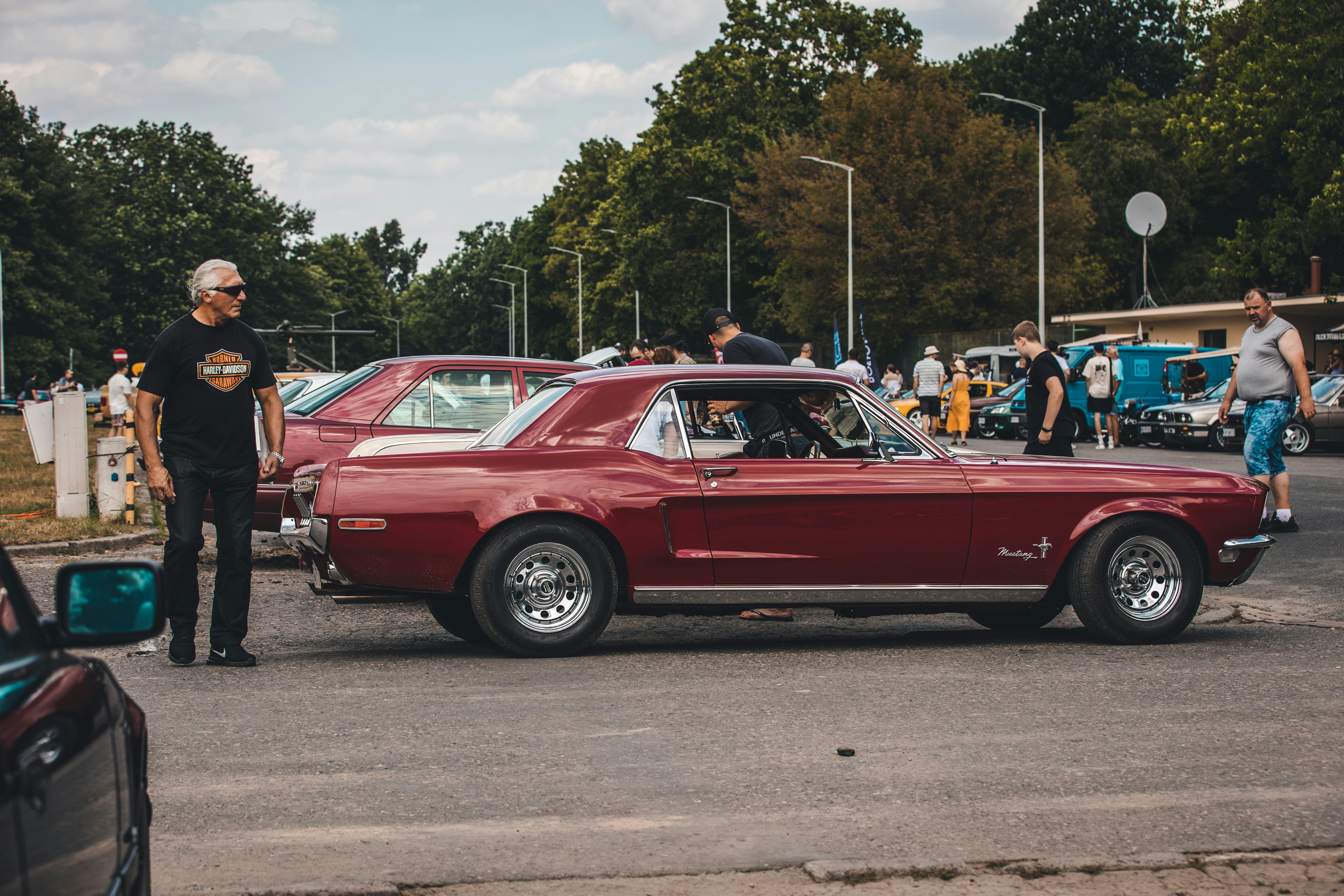 a man standing next to a red car in a parking lot