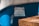 A handwritten sign is taped to the side of a blue vehicle or object. The sign is made of paper with text in Polish, secured with pieces of tape at the corners. There is a wicker basket or similar object partially visible in the foreground.