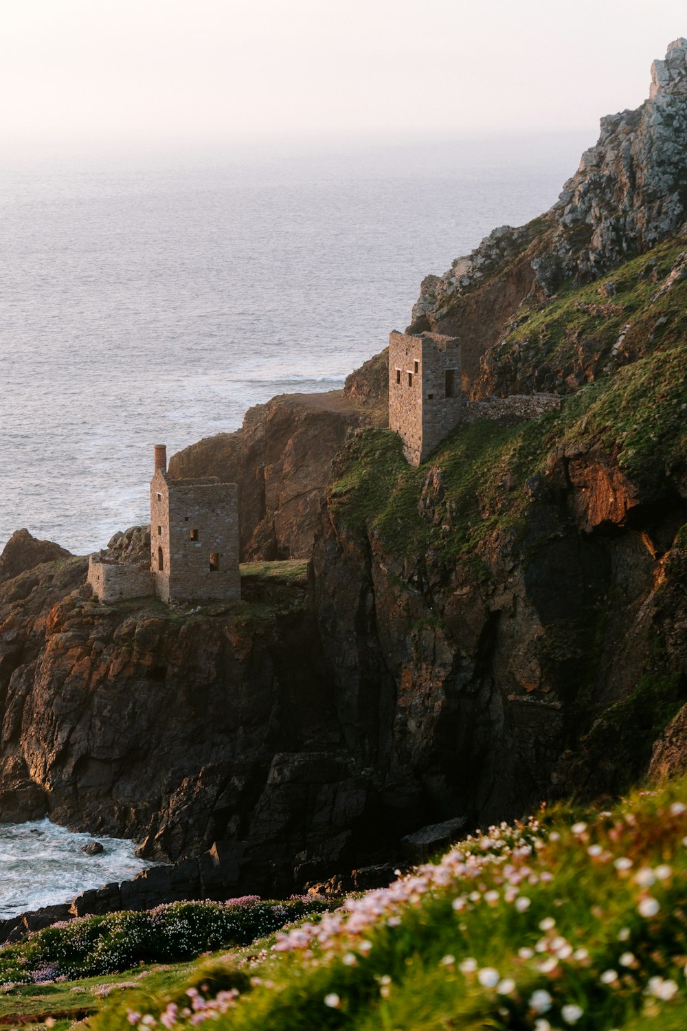 a cliff with a house on top of it next to the ocean