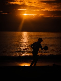 Sunset silhouette of a player throwing a baseball, embodying dedication and focus.