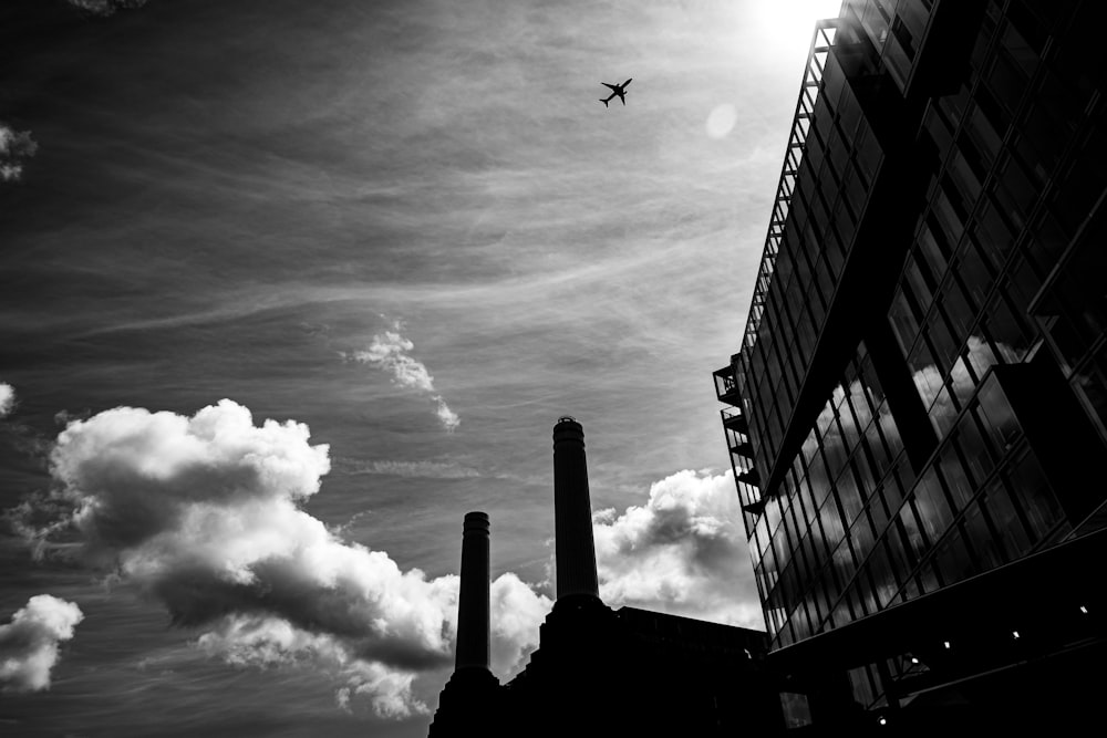 a plane flying over a tall building under a cloudy sky