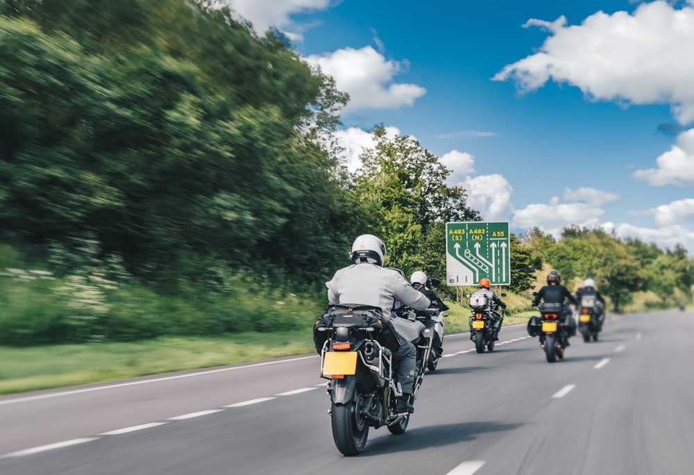 a group of people riding motorcycles down a road
