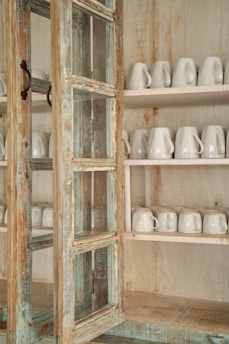 A rustic farmhouse wooden hutch cabinet filled with vintage dishes and glassware.