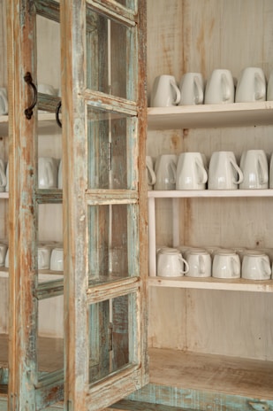 A rustic farmhouse wooden hutch cabinet filled with vintage dishes and glassware.