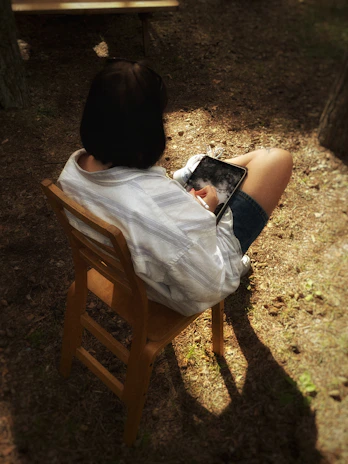 A relaxed person enjoying a Blackburn strategy game outdoors on a tablet during golden hour.
