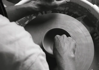 Hands molding clay in a pottery class, capturing the tactile art experience.