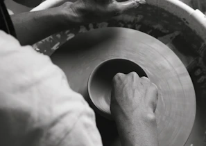 Hands shaping a piece of clay on a pottery wheel, capturing the craft in motion.