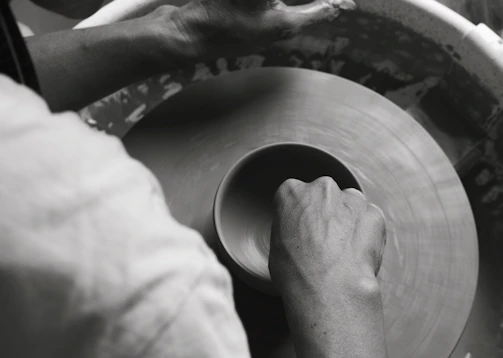 Artisan hands shaping fresh molela terracotta clay into a ring, capturing the craft in motion.