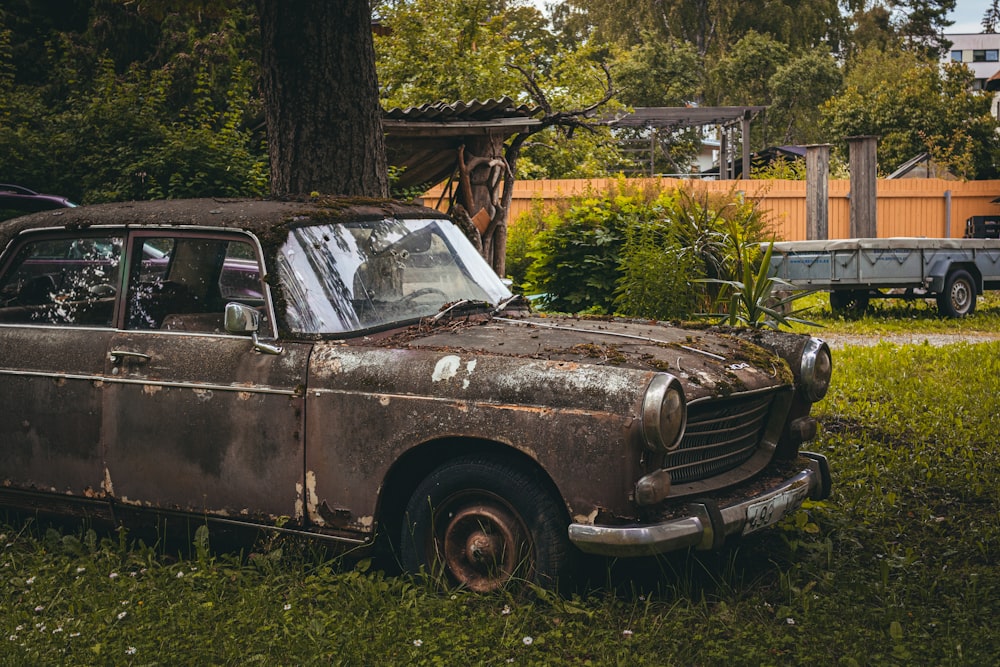an old rusted car sitting in the grass