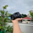 A happy customer holding a UBM Canon camera outdoors, smiling with a scenic background.
