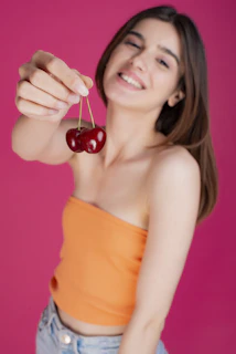 A cheerful author photo of a smiling woman holding a basket of fresh fruits and supplements outdoors