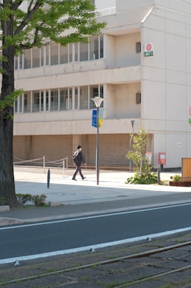 a man walking down a street next to a tall building
