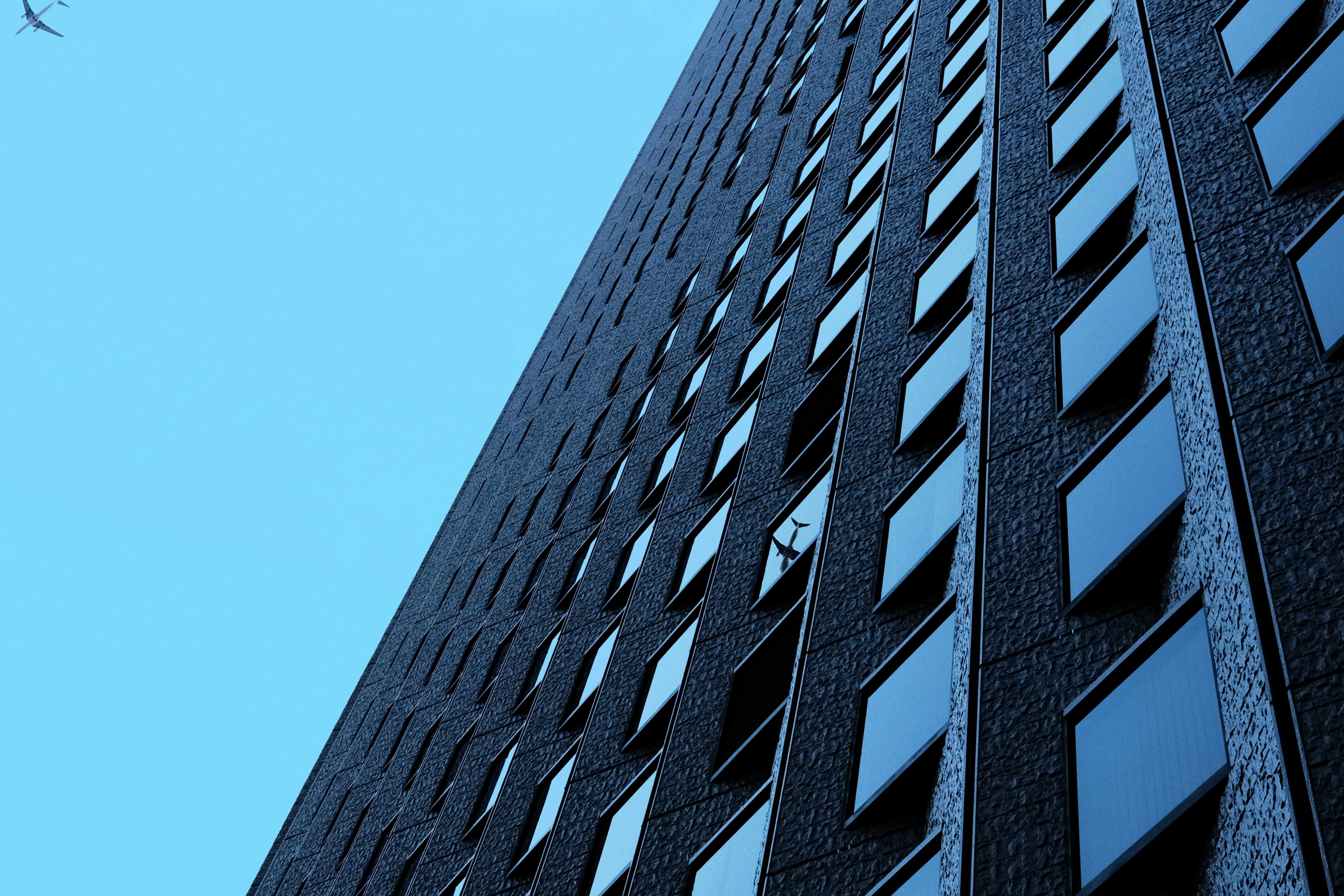 a plane flying in the sky near a tall building