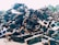 A large pile of metal scrap and debris is stacked outdoors. The metal pieces are of various shapes and sizes, with some showing signs of rust and wear. Sunlight is cast over the pile, highlighting the angular shapes and textures.