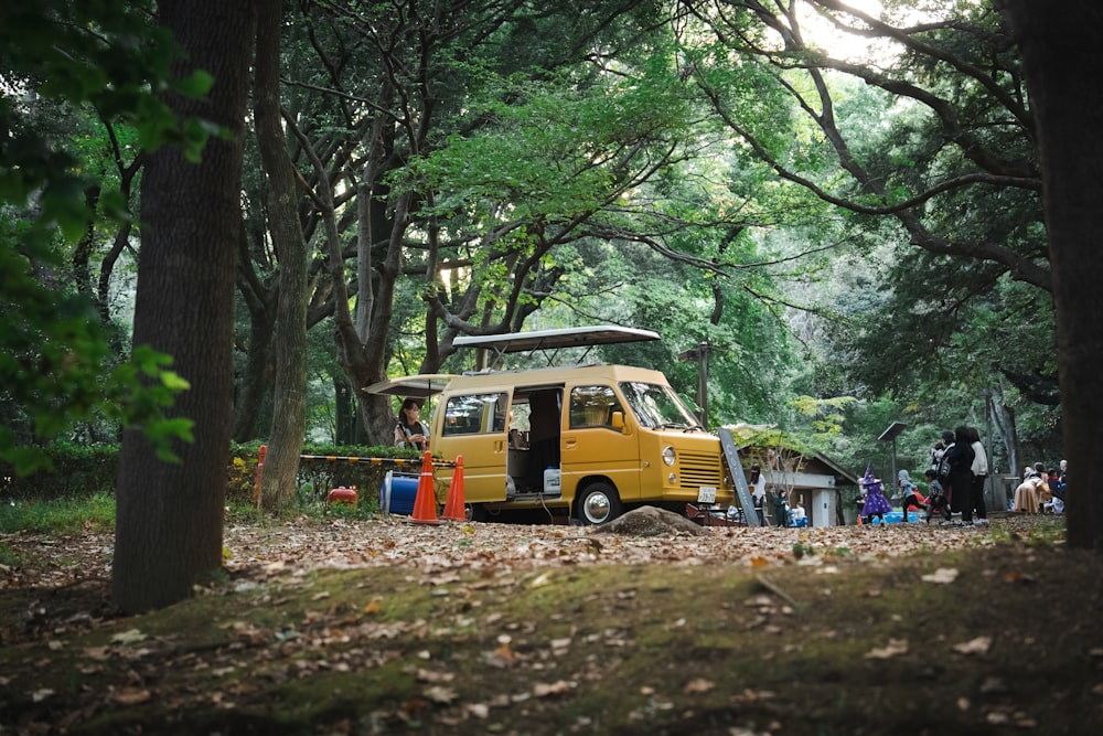 a van is parked in the woods with people around it