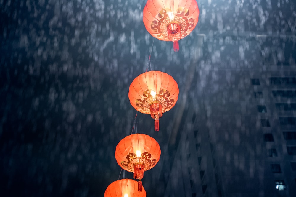 three red lanterns hanging from a ceiling in the rain