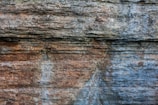 Rugged rock face with layered textures and variations in color, showcasing natural erosion and geological patterns.