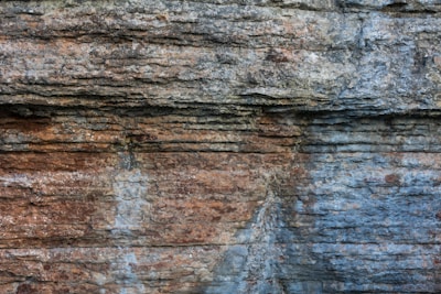 Rugged rock face with layered textures and variations in color, showcasing natural erosion and geological patterns.