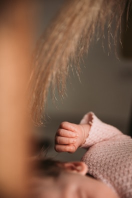 A close-up of tiny baby hands resting softly on a warm-toned textured blanket with subtle glow effects.