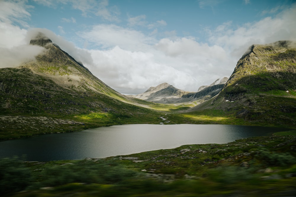 a lake surrounded by mountains under a cloudy sky