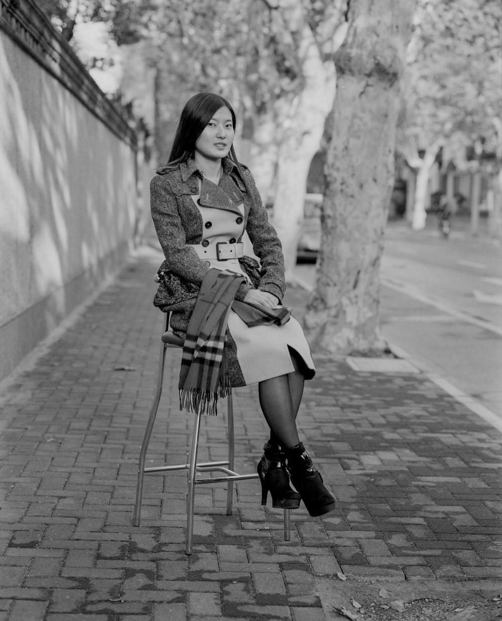 a woman sitting on a chair on a sidewalk