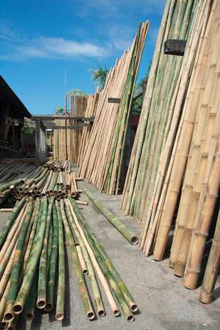 Artisan hands shaping smooth bamboo poles ready for export.
