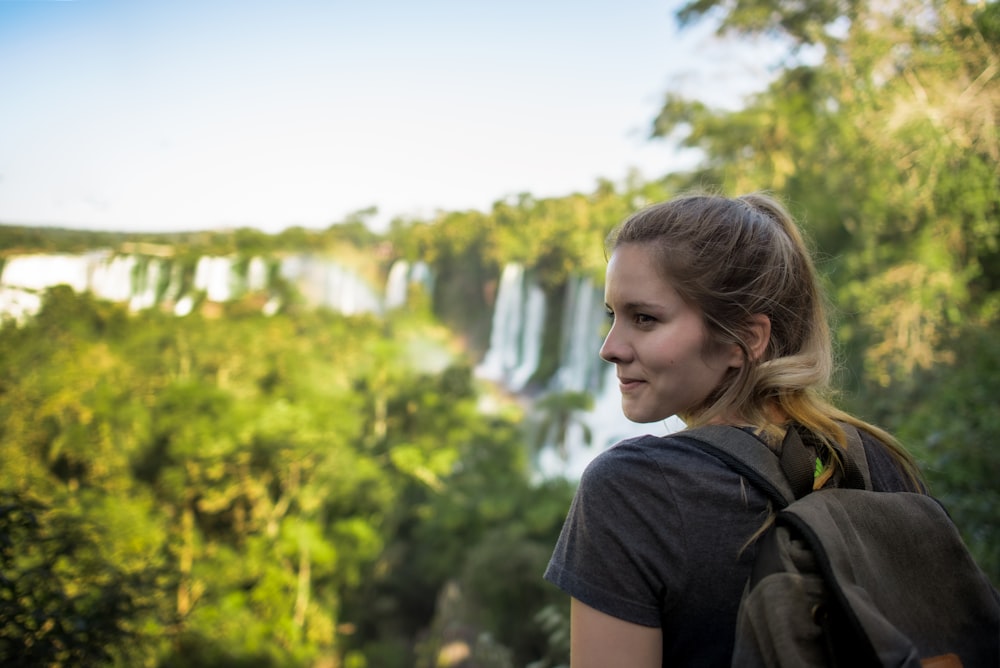 a woman with a backpack looking at a waterfall