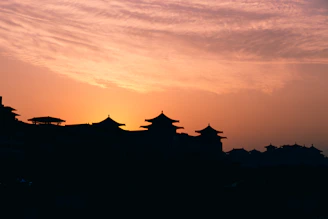 Sunset over the ancient town of Lijiang with traditional rooftops and mountains in the background.