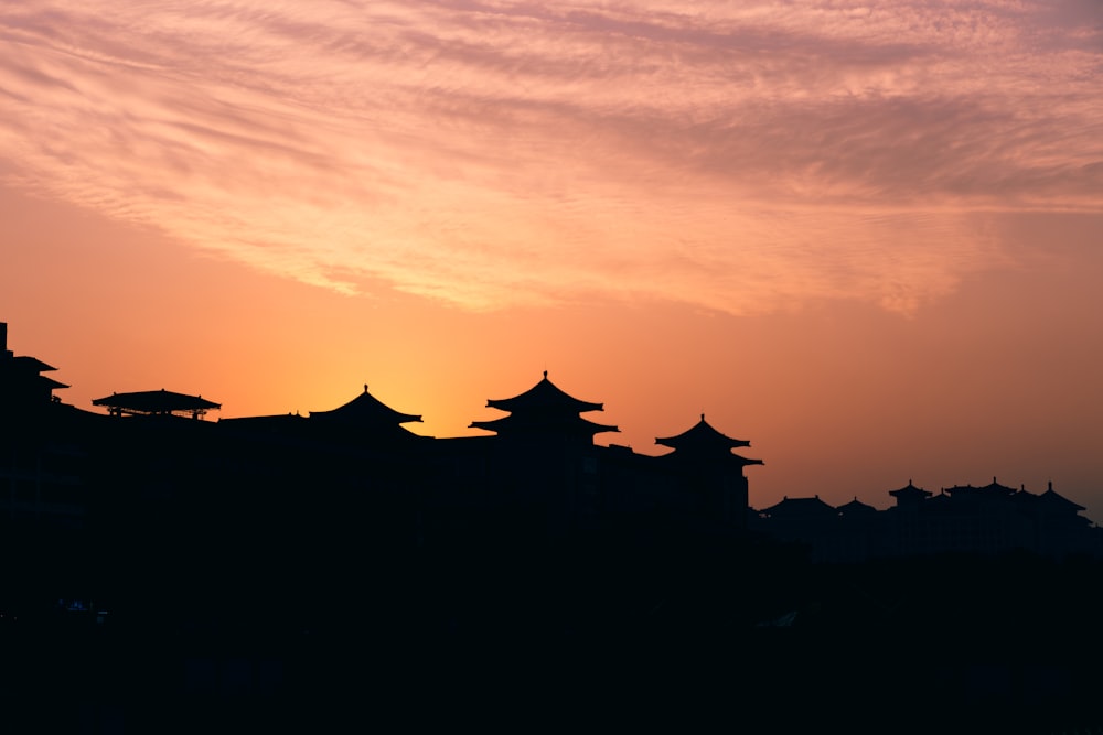 the sun is setting behind a building with pagodas