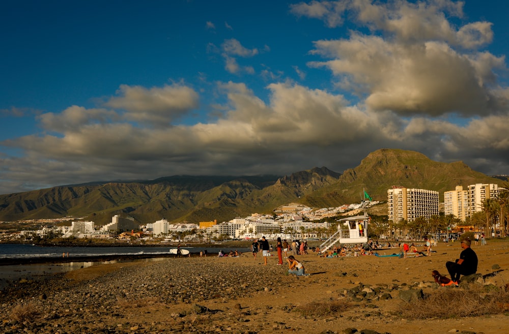 a group of people on a beach with mountains in the background