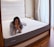 Close-up of a comfortable mattress in a bright, cozy bedroom setting.
