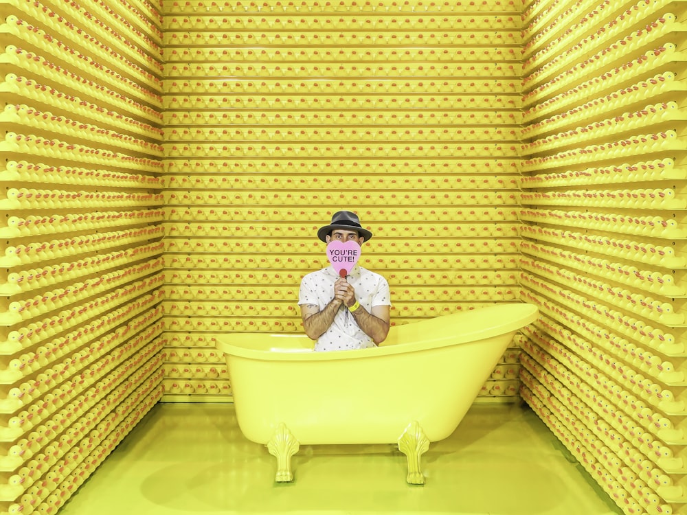 a man in a hat is in a yellow bathtub