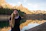 a woman standing in front of a lake with mountains in the background