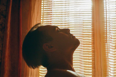 Person meditating peacefully with soft light filtering through a window.