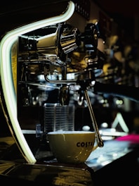 A skilled technician carefully repairing a sleek commercial espresso machine in a bright, modern workshop.