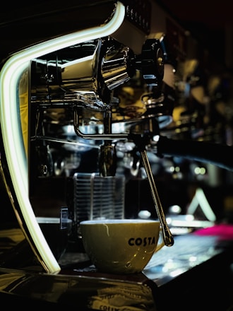 A skilled technician carefully repairing a sleek commercial espresso machine in a bright, modern workshop.