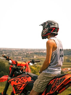 A rider wearing a helmet looking out over a vast desert landscape at sunset.