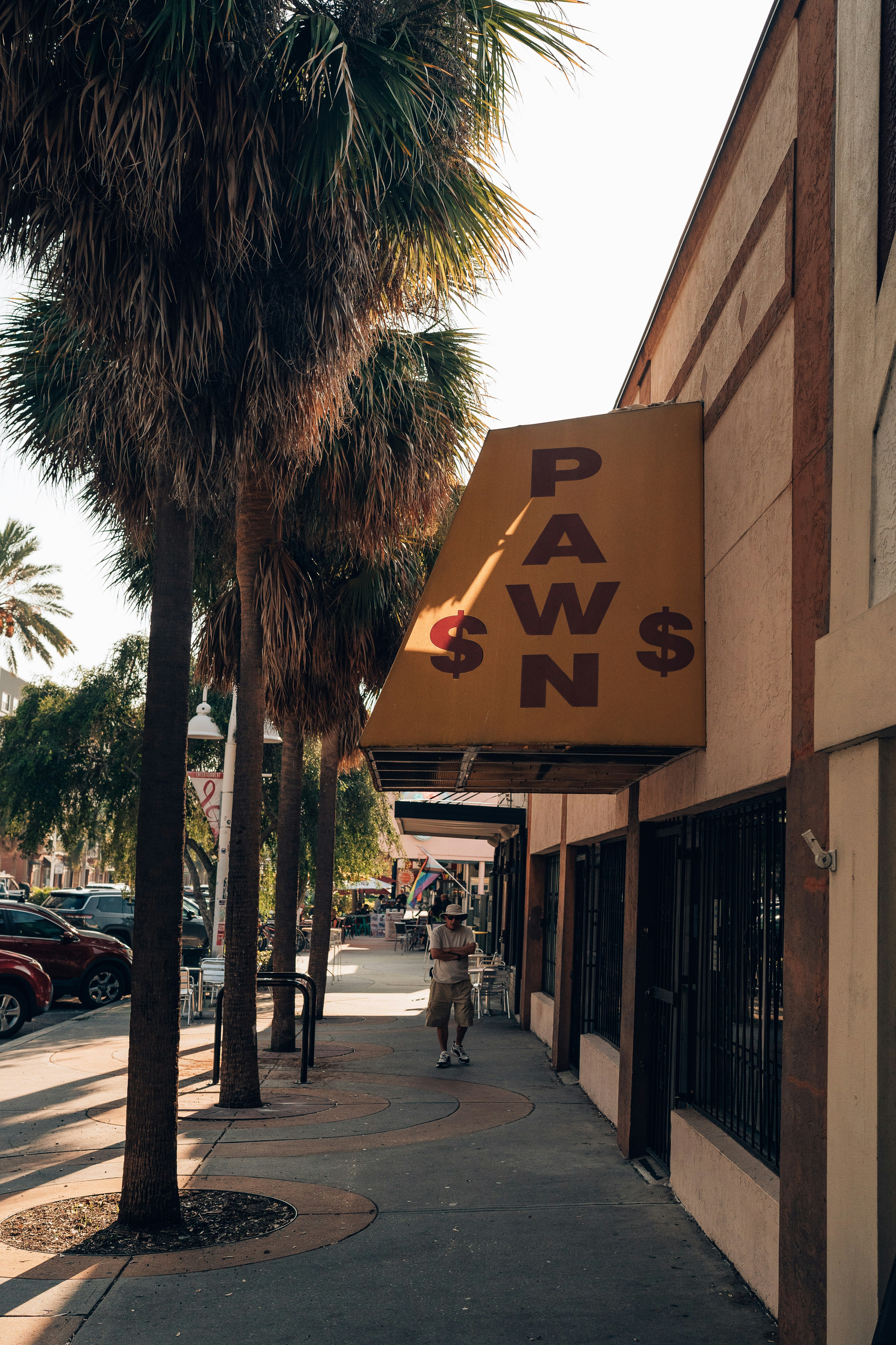 a person walking down a sidewalk next to palm trees