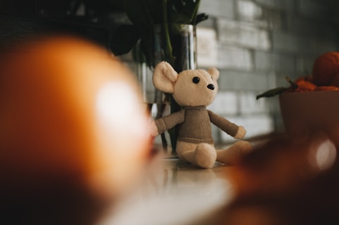 a teddy bear sitting on a counter next to a vase of flowers